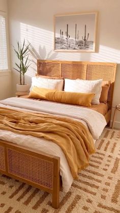 a bed with yellow blankets and pillows in a bedroom next to a plant on the floor