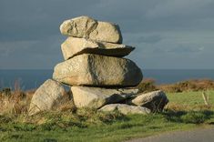 a pile of rocks sitting on top of a lush green field next to the ocean