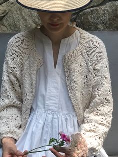 a woman in a white dress and hat holding flowers