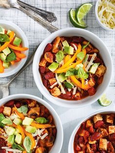 three white bowls filled with chili, tofu and cheese on top of a table