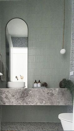 a white toilet sitting next to a sink in a bathroom under a mirror above it