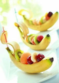 some fruit shaped like banana boats on a white plate