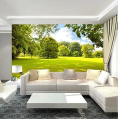 a living room with white furniture and green trees on the wall behind the couches