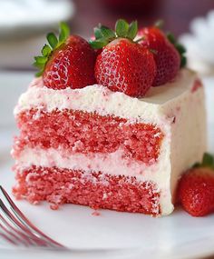 a piece of red velvet cake with white frosting and fresh strawberries on top