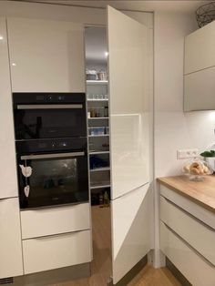 a modern kitchen with white cabinets and wood counter tops, along with an oven in the corner