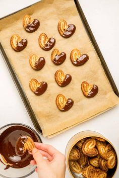 someone is dipping some chocolate into small heart shaped pretzels