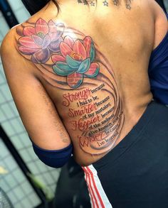 the back of a woman's shoulder with flowers on it and words written in cursive writing