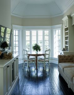 a dining room table and chairs in front of large windows