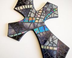 a cross made out of stained glass on a white wall