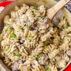 a pot full of pasta with meat and parsley in it on a red cloth