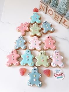 decorated cookies arranged in the shape of christmas trees on a white table with a wooden sign