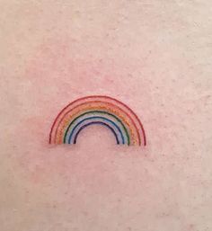 a small rainbow tattoo on the back of a woman's left upper arm and shoulder