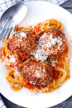 spaghetti and meatballs on a white plate with a fork