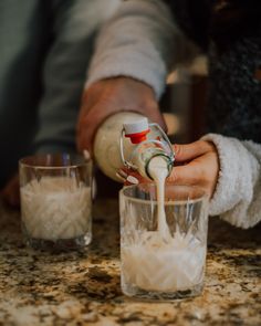 someone pouring something into a glass on top of a counter