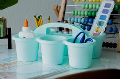 plastic cups with markers, pens and pencils in them on a table next to an abacus