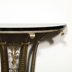 an ornate console table with marble top and gold trim around the edges, against a white wall