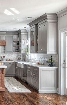 a large kitchen with wooden floors and gray cabinets