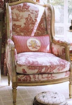 an ornate chair and footstool in front of a window with pink flowers on it