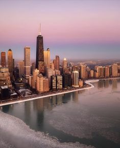 an aerial view of a large city with tall buildings and ice on the water in front of it