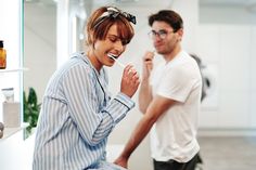 a man and woman brushing their teeth in the bathroom