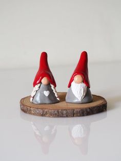 two gnome figurines sitting on top of a piece of wood