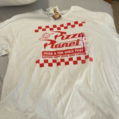 White Tee Shirt With Red Checker Board Text Says: Pizza Planet Food & Fun Space Port Serving Your Local Star Cluster Pixar/Disney Pizza Planet, White Tee Shirt, Checker Board, Food Shirt, Star Cluster, Red Checkered, White Tee Shirts, Disney Shirts, White Tee