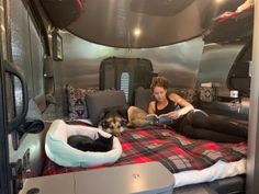 a woman sitting on top of a bed next to a black and white dog laying down