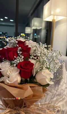 a bouquet of red and white roses sitting on top of a table