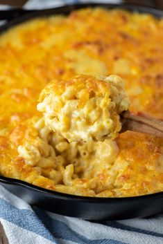 a skillet filled with macaroni and cheese being scooped from the casserole