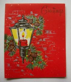 a red christmas card with a lit candle and pine cones