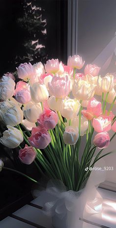 a vase filled with pink and white tulips sitting on top of a window sill