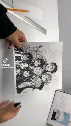 a person is drawing on a piece of paper next to a pen and some pictures