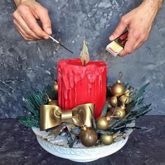 a person is decorating a red candle with gold ornaments and spray paint on it