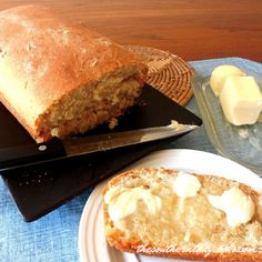 a loaf of bread sitting on top of a white plate next to a knife and butter