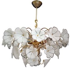 a chandelier with white flowers hanging from it's golden metal frame and chain