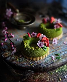 two small cakes with flowers on them sitting on a cutting board next to a spoon