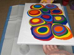 a person holding up a large colorful art piece on top of a sheet of paper