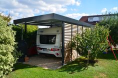 a white van is parked in the shade under a canopy over it's back door