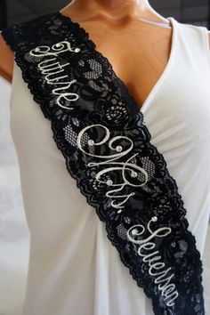 a woman wearing a black lace sash with the word bride written in white on it