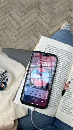 an open book sitting on top of a person's lap next to a cell phone