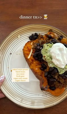 a white plate topped with a piece of bread covered in black beans and guacamole