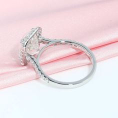 a diamond ring on top of a pink cloth