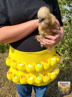 a woman is holding a chicken in her yellow crochet skirt with hearts on it