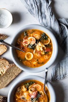 two bowls of soup with bread on the side