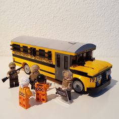 three lego figures are standing in front of a school bus