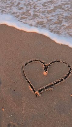 a heart drawn in the sand at the beach