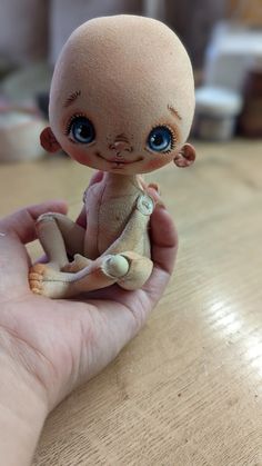 a hand holding a small doll on top of a wooden table