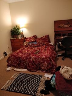 a bedroom with a bed, desk and chair in it's corner area next to a lamp