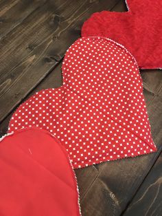 three red heart shaped pieces laying on top of a wooden floor