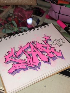 a notebook with pink graffiti on it sitting on top of a table next to other items